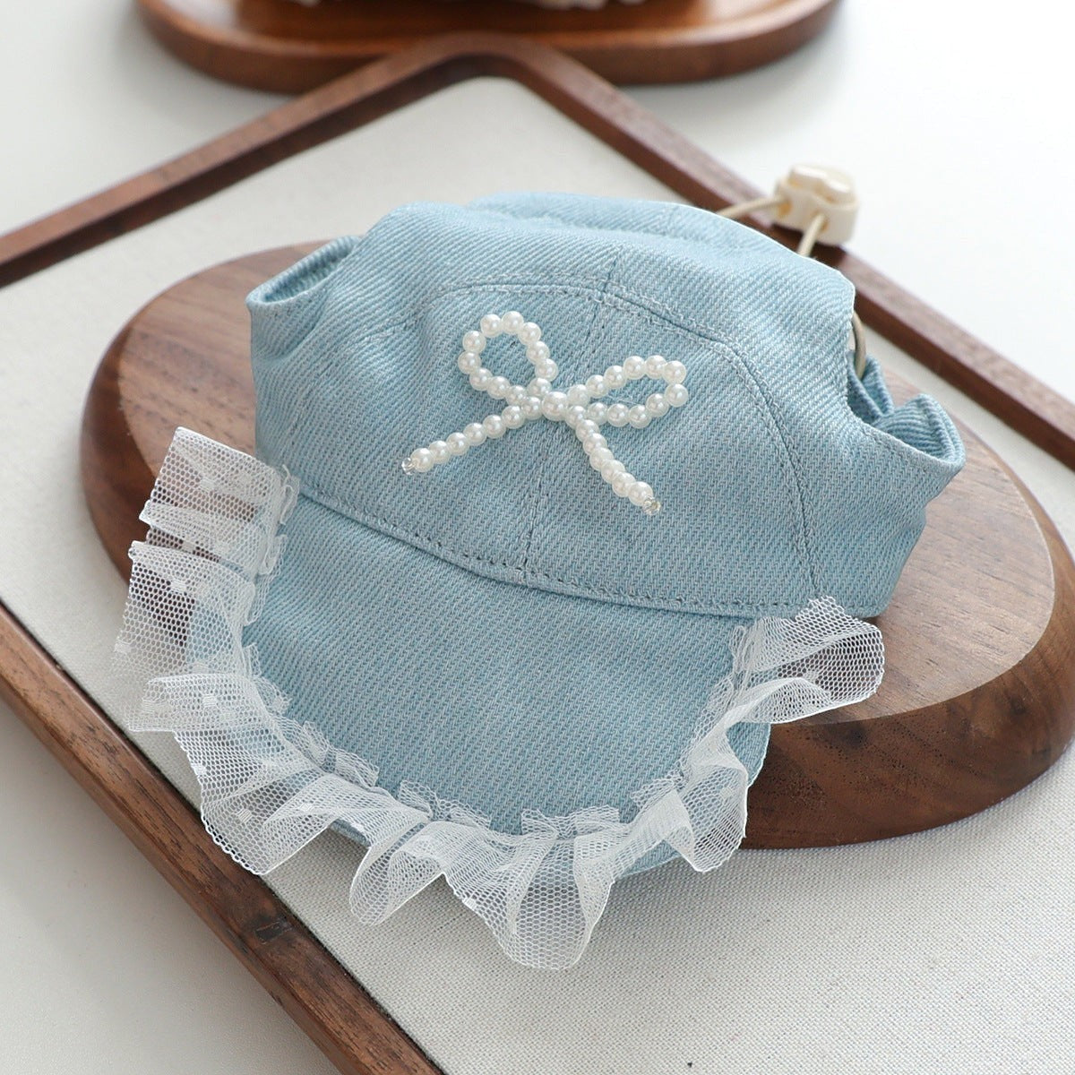The Spoiled Pet Club light blue denim pet sun hat with a white pearl bow and delicate lace trim detail.