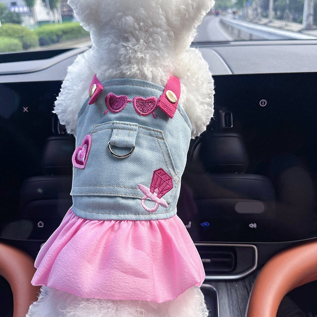 The Spoiled Pet Club denim pet dress with pink skirt, heart embroidery, and pacifier detail on a white dog in a car.