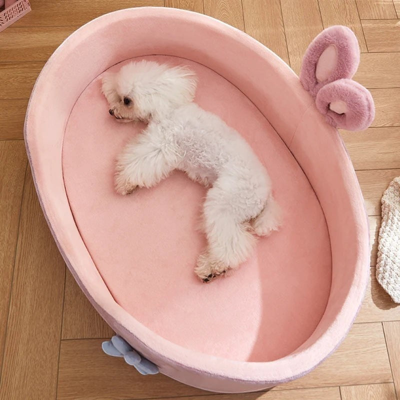 The Spoiled Pet Club Little Haven Bed, a plush pink oval pet bed with raised edges and bunny ears, perfect for small dogs.
