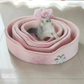 The Spoiled Pet Club pink plush pet bed with raised edges and flower detail, featuring a silver tabby kitten.